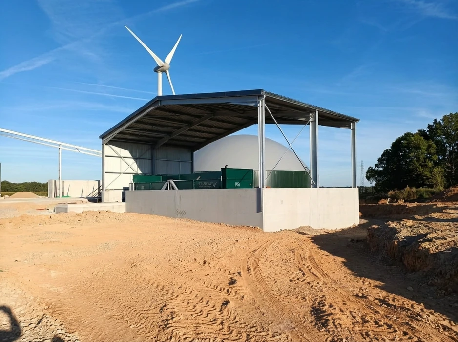 Bâtiment agricole moderne avec bardage métallique bi-couleur, situé au milieu d'un champ de cultures vertes