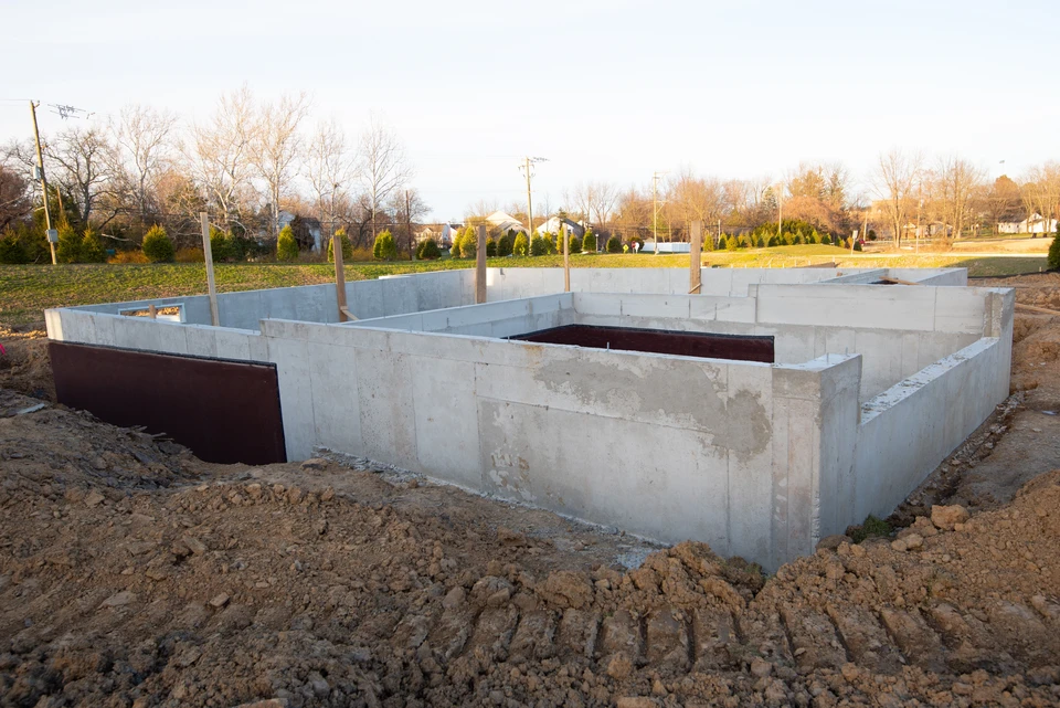 Chantier de construction en extérieur avec ouvriers en équipements de protection individuelle travaillant sur une dalle béton